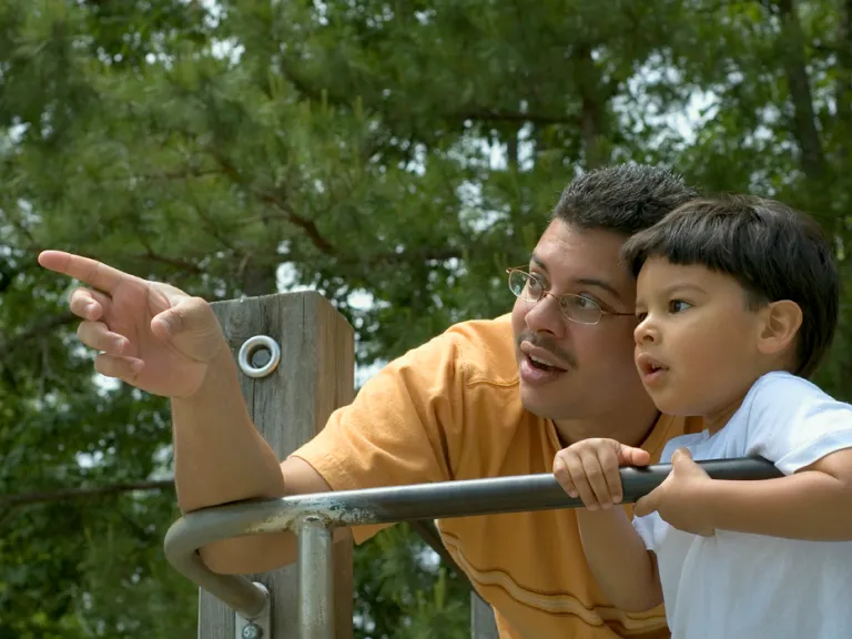 A dad and son playing at a park.