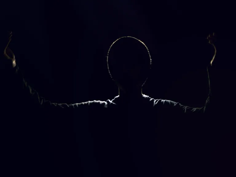 A shadow silhouette of a man with arms in the air.