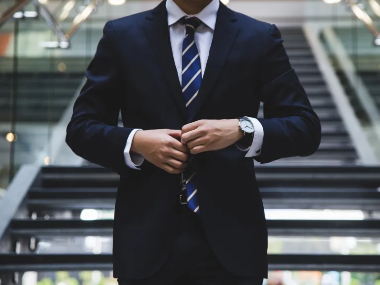 Photo of a man buttoning a tailored suit.