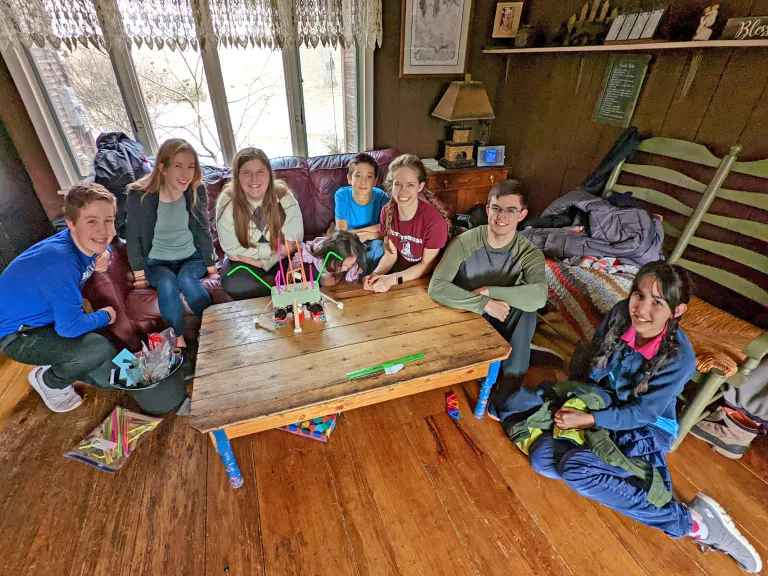A group of teenagers gathered around a project on a table