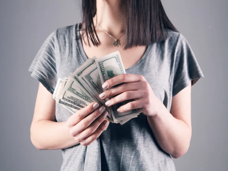 a woman holding one-hundred dollar notes