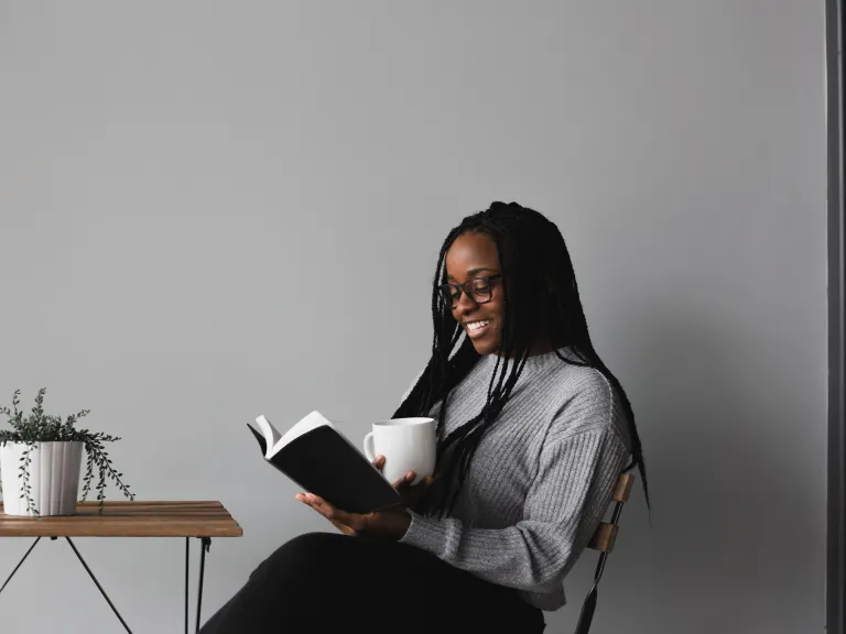 a woman holding a coffee cup and reading a Bible