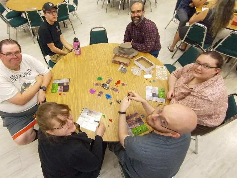 six people gathered around a table playing games