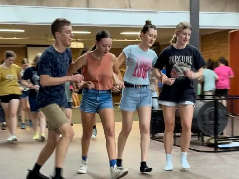 a group of campers arm in arm for a dance