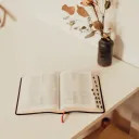 Une Bible à côté des fleurs dans un vase sur une table