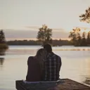 A couple sitting beside each other on a boat dock.